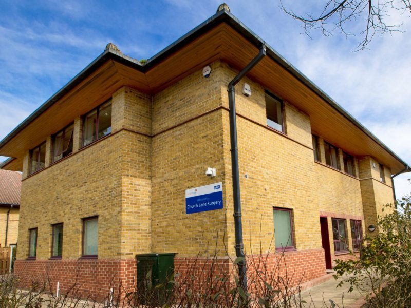 Image is a photo of Church Lane Surgery with a blue sky in the background